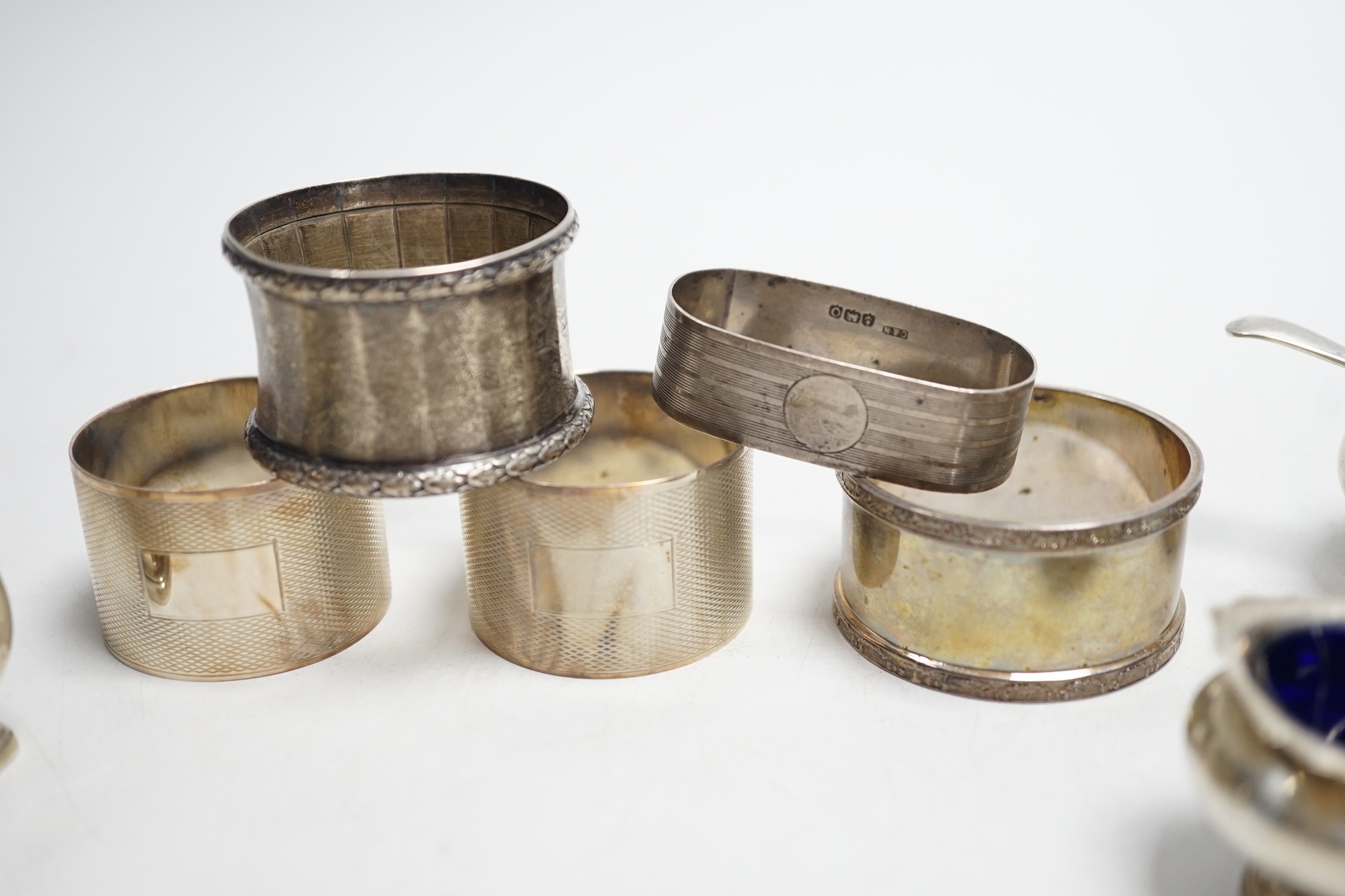 Five assorted silver napkin rings and a George V silver three piece condiment set.